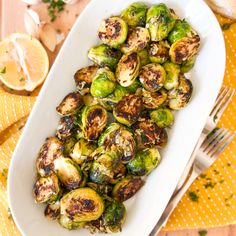 brussel sprouts in a white dish on a yellow place mat with silverware