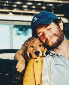 a man holding a dog in his arms while wearing a blue hat and yellow jacket