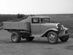 an old truck is parked on the side of the road in front of a field