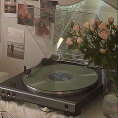 a record player sitting on top of a table next to a vase filled with flowers