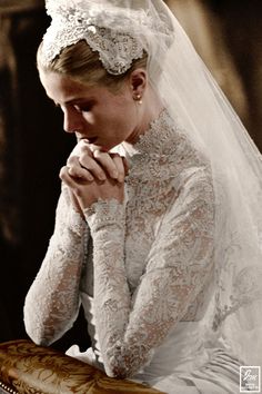 a woman in a white dress and veil is holding a red purse with her hands