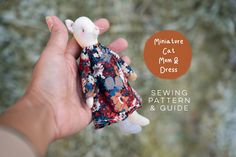 a hand holding a miniature cat doll in a floral dress with the text miniature cat & dress sewing pattern and guide