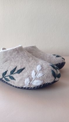 a pair of slippers with leaves on them sitting on top of a white table