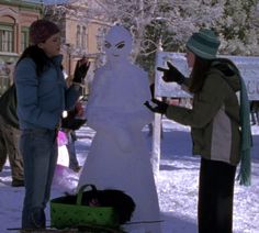 two women standing in front of a snow man