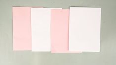 three pieces of pink and white paper on a table