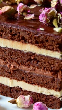 a piece of chocolate cake on a white plate with pink flowers around it and two slices cut out