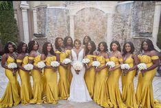 a group of women standing next to each other wearing yellow dresses and holding bouquets