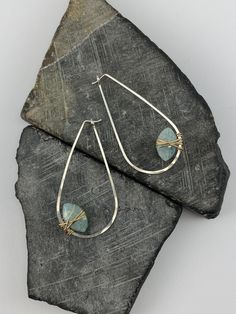 Where Nature Meets Luxury: These stunning earrings showcase the mesmerizing beauty of aquamarine gemstones, meticulously wrapped within a delicate sterling silver hoop with 14k gold fill wire. The teardrop shape and vibrant blue hue of the aquamarine create a piece of jewelry that is both elegant and effortlessly captivating.  The Enchantment of Aquamarine: Aquamarine, known for its tranquil blue color, is believed to symbolize peace, serenity, and emotional balance.  Associated with the throat chakra, it is said to promote clear communication and self-expression. Handcrafted with Care: Each pair of earrings is meticulously crafted using high-quality materials and time-honored techniques. The delicate setting of the aquamarine ensures its beauty shines through, while the sterling silver an Silversmith Earrings, Teardrop Hoop Earrings, Tranquil Blue, Mesmerizing Beauty, Jewelry Design Inspiration, Earrings Teardrop, Clear Communication, March Birthstone, Emotional Balance