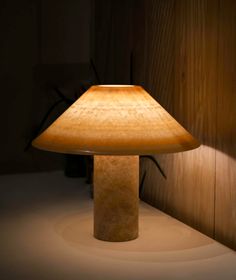 a table lamp sitting on top of a white counter next to a wooden wall and floor