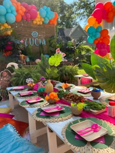 a table set up for a party with balloons and plates on it, along with other decorations