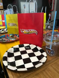 a table topped with plates and paper bags filled with hot wheels merchandise on top of a wooden table