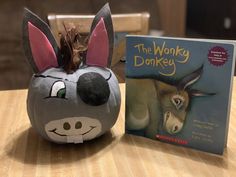 a stuffed animal next to a book about the wonky donkey on a wooden table