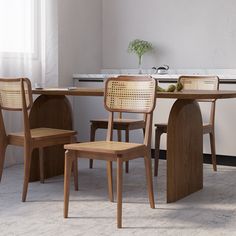 a dining room table with four chairs and a vase on the counter in front of it