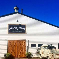 an old truck parked in front of a white building with a sign that says sycamore farms