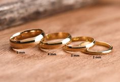 three different sizes of wedding rings sitting on top of a wooden table next to each other