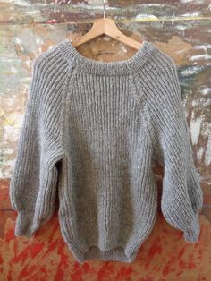 a gray sweater hanging on a wooden hanger