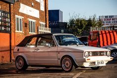 an old car parked in front of a brick building