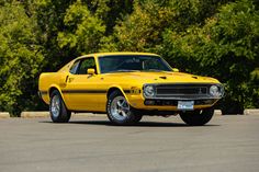 a yellow muscle car parked in a parking lot