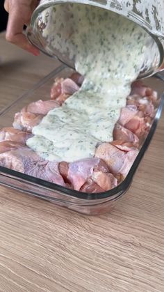 a person pouring dressing into a container filled with meat