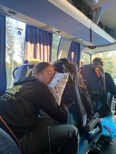 two people sleeping on the back of a bus with their backs turned to the side