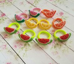 several pieces of fruit are arranged on a table with pink flowers and green rings in the middle