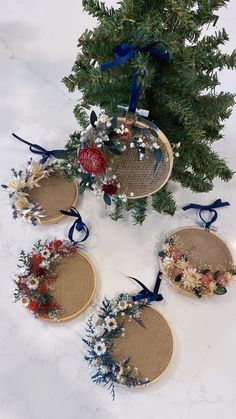 four baskets with flowers on them are sitting next to a christmas tree in the snow