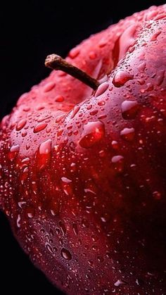 an apple with water drops on it is shown in this close up photo, against a black background