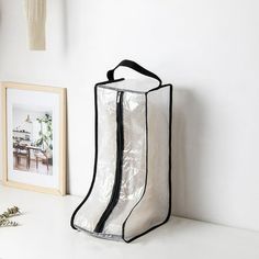 a clear boot bag sitting on top of a white counter next to a framed photograph