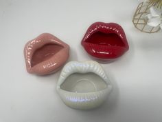 three different types of mouth shaped vases on a white surface with flowers in the background