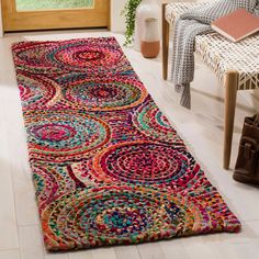 a multicolored area rug on the floor in front of a chair and window