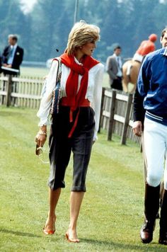 two women walking in the grass with jockeys behind them