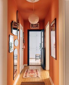 an orange hallway with pictures on the wall and mirrors hanging from it's ceiling