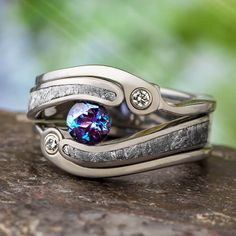 a couple of silver rings with a blue stone in the middle on top of a rock