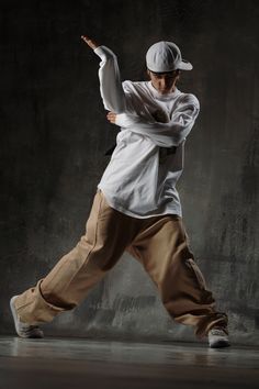 a man in white shirt and khaki pants doing a dance move with his arms stretched out