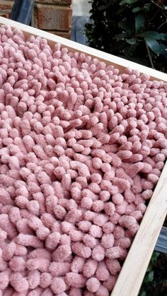 a wooden box filled with lots of pink pom - poms on top of a table