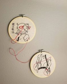 two embroidery hoops with drawings on them hanging from the wall