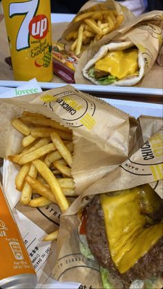 two trays filled with hamburger and french fries next to a cup of orange juice