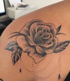 a rose tattoo on the back of a woman's shoulder, with water drops