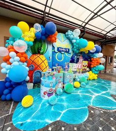 balloons and decorations are set up on the ground for a pool party with an inflatable pineapple theme