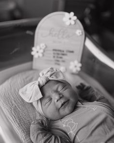 a black and white photo of a baby in a crib with a birth sign