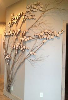 a large metal tree with white flowers on it's branches is mounted to the wall