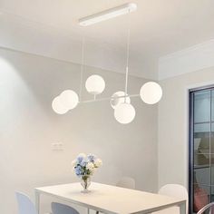 a white dining room table with four chairs and a vase of flowers on the table