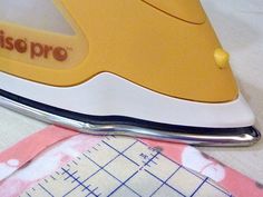 a yellow and white iron sitting on top of a table next to a piece of cloth