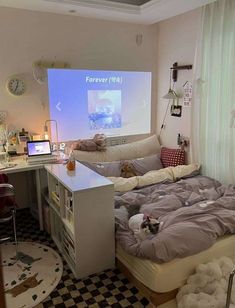 a room with a bed, desk and projection screen in the corner on the wall