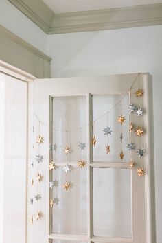 an open window with star garland hanging from it's sides in front of a white wall