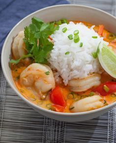 a white bowl filled with shrimp, rice and cilantro on top of a table