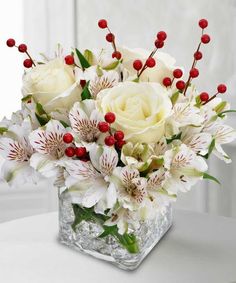 a vase filled with white flowers and red berries