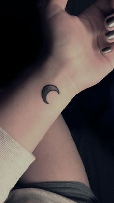 a woman's arm with a small crescent tattoo on her left wrist and the moon in the middle