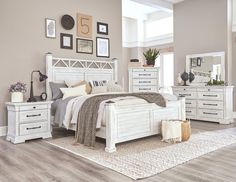 a white bed sitting on top of a wooden floor next to a dresser and mirror