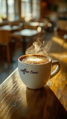 a cup of coffee sitting on top of a wooden table with steam coming out of it